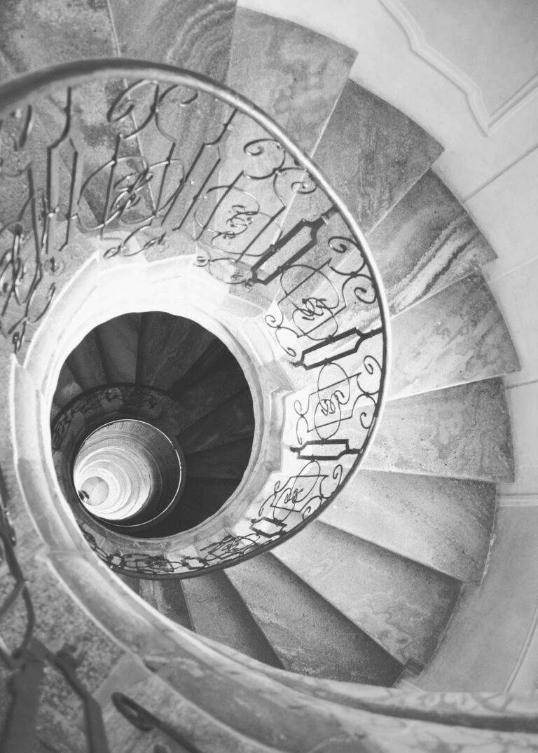 Czarno-białe kręte schody prowadzące w głąb budynku na dół